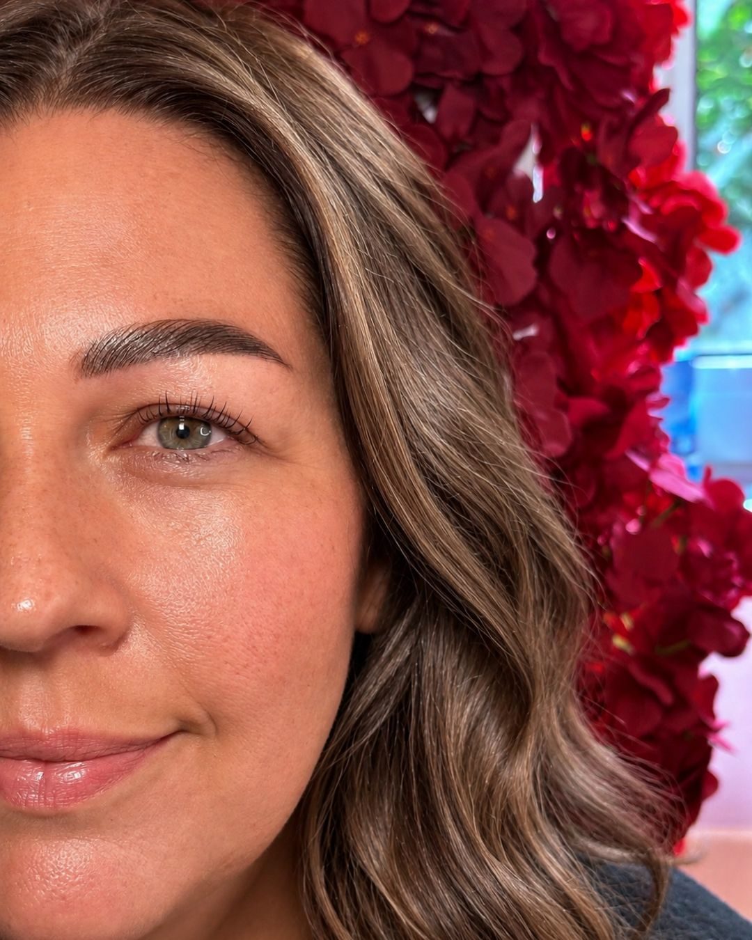 Kundin nach dem Brow- und Lashlifting vor der Rosenwand